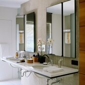Large double washstand with Corian countertop and asymmetrical tilting mirrors on concrete partition