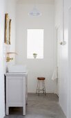 Vintage Kommode als Waschtisch mit rechteckiger Waschschüssel und goldener Wandarmatur; an der Wand ein goldgerahmter Spiegel