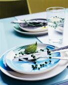 Stalk of berries and flower bud decorating place setting and in glass of water on table