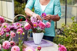 Woman arranging vase of summer flowers in garden