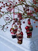 Father Christmas baubles hanging on branches of red berries