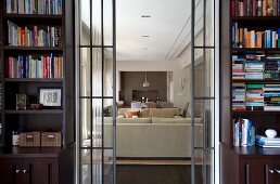 Open sliding glass doors flanked by bookcases and view of pale sofa set in modern living room