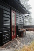Autumn mist over wooden house with terrace and wooden corner bench