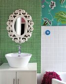 White wash basin on base unit and retro mirror on wall with green mosaic tiles