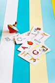 Kinderkreisel und Buchstabenkarten auf verschiedenfarbig bemalten Holzleisten