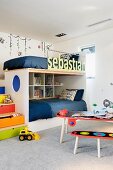Gemütliches Stockbett im Kindrzimmer mit farbenfroher Schubladentreppe und Geländer mit Namenszug