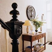 Staircase balustrade with black newel post and spherical finial in front of console table