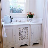 Washstand with carved panel in white base unit below window in niche