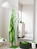 Housecoat hanging on a green metal clothes stand next to a wall mirror in the corner of a bedroom