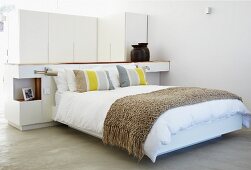Modern double bed with throw against partition in sleeping area