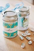 Decorated and labelled metal cans as gifts and silver decorative pebbles