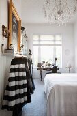 Bedroom with double bed, skirts hanging up and antique escritoire below window