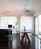 Essplatz mit rustikalem Holztisch zwischen freistehender Küchentheke und Terrassenfront in offenem Wohnraum