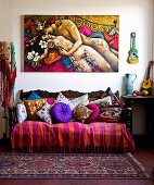 Antikes Sofa mit farbenfroher Decke und Kissensammlung unter buntem Gemälde mit Liebespaar