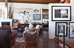 Various armchairs in lounge area and collection of modern artworks on walls in open-plan interior
