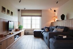 Living room with TV, sofa combination and media cabinet integrated into wooden dado