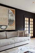 Ecru sofa below modern artwork on black-painted wall next to lattice doors