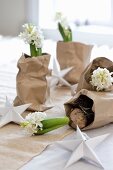 Weiß blühende Hyazinthen als weihnachtliche Tischdeko in geknautschte Packpapiertüten gestellt