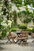 Gartentische und -stühle zwischen Rosen und Buchsbaumhecken