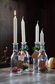 Kerzen in Flaschen mit Nummernkärtchen und Pflanzendeko