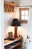 Artistic table lamp with wooden base and leather lampshade below country-house coat rack