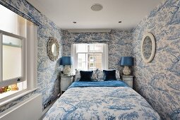 Kühler Schlafraum in Weiß und Blau mit durchgehendem, blauen Baummotiv auf Wandtapete und Textilien