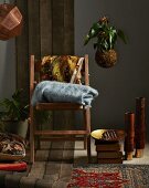 Winter shopping trends: woollen blanket on wooden chair, floor cushions, rugs and lamps