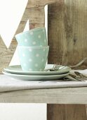 Polka dot cups and plates and cutlery on wooden surface