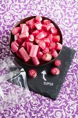 Bowl of red boiled sweets on slate board with stamped motif