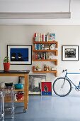 Island kitchen counter on castors and designer, plexiglass stools (Ghost); various artworks, bookshelves and racing bike against wall in background