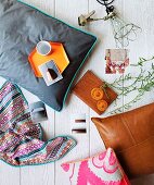 Still-life arrangement of cushions, photos and various home accessories on white-painted wooden surface