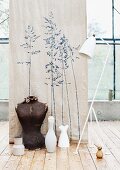 Wall decal of grasses on old linen fabric behind vintage standard lamp, tailors' dummy and vases