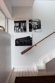Treppenhaus mit Vintage Holz Handlauf und schwarz-weiße Fotos an Wand