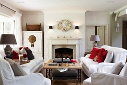 weiße Polstersofas und Couchtisch vor offenem Kamin in traditionellem elegantem Landhaus Wohnzimmer