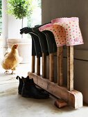 Wellington boots on vintage wooden rack; hen on veranda in background