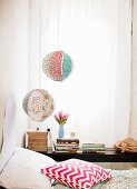 Zwei romantische Laternen mit verschiedenen Stoffmustern beklebt, hängen vor abgeschattetem Fenster im Schlafzimmer