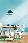 Lampshade wrapped with colourful wool above tulip table and white metal chairs