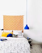Hand-crafted wall hanging on white wall above comfortable double bed