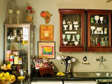 Collection of antique crockery in antique display cabinets on wall above kitchen counter in corner
