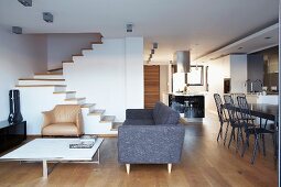 Open-plan living area in architect-designed house with minimalist furnishings and staircase without handrail