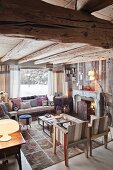 Chairs and comfortable couch below window in chalet interior with open fire