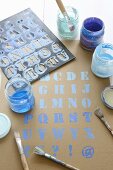 Letter stencil, paintbrushes and blue paint