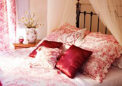 Kissen mit teilweise rotem Satinbezug und gemustertem Bezug auf Bett in traditionellem Schlafzimmer
