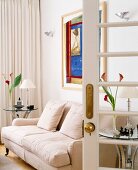 Blick in Wohnzimmer mit beiger Couch & Beistelltischchen aus Glas