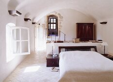 Doppelbett mit angebauten Nachttischchen in Schlafraum mit Rundbogendecke