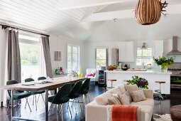 Langer Esstisch mit Klassikerstühlen (Executive von Saarinen), Sitzbereich mit Sofa und offene Küche mit Frühstücksbar