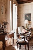 Nostalgischer Schreibplatz mit antikem Sekretär und Armlehnstuhl vor geöffnetem Sprosssenfenster in Zimmerecke