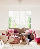 Pink colour accents in living room; sofa cushions, flowers, ottoman and pouffe