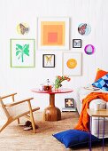 Unusual red table with solid wooden base in bright bedroom with colourful collection of artworks on wall