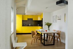 Einbauküche mit gelben Fronten und Designer Esstisch im offenen Grundriss eines Lofts